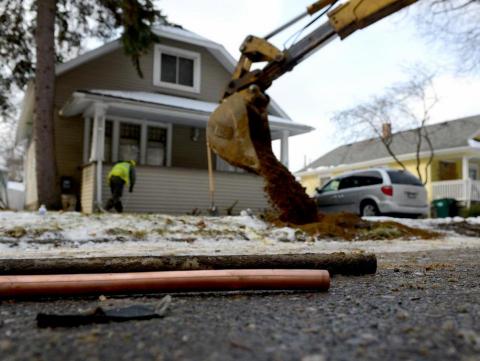 As the hole is filled in in the background, a piece of an old lead water pipe sits next to a new copper pipe